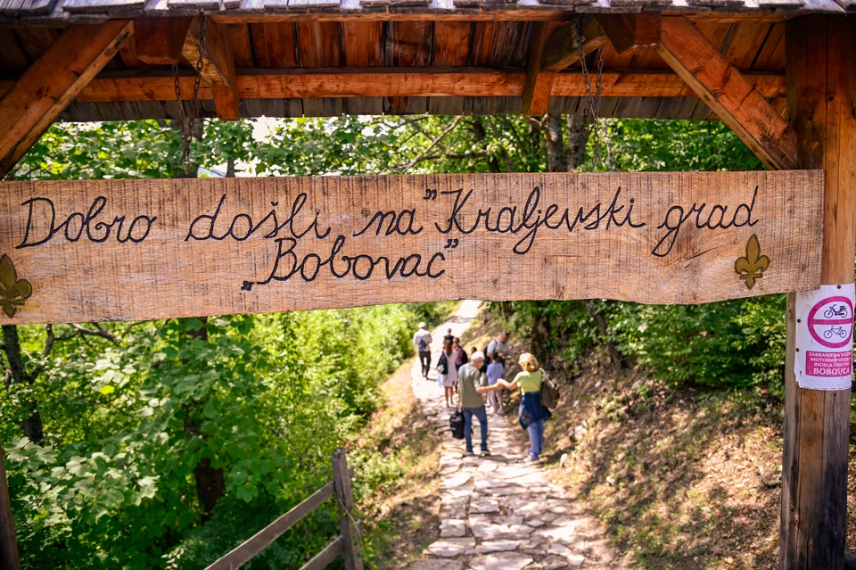 Drvena tabla dobrodošlice na Bobovac iznad kamene staze kojom prolaze posjetioci